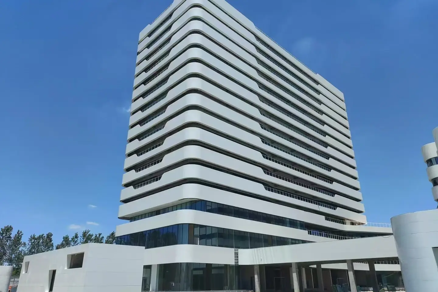 White multi-storey hospital building clad in white crystallized glass panels