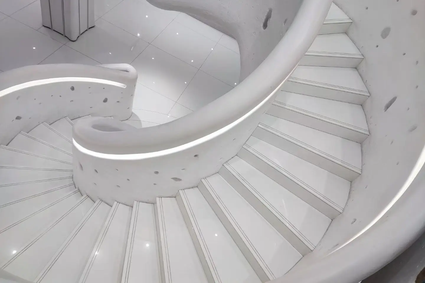 White curved spiral staircase with continuous rounded balustrade